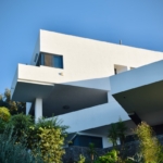 white concrete building near green trees under blue sky during daytime
