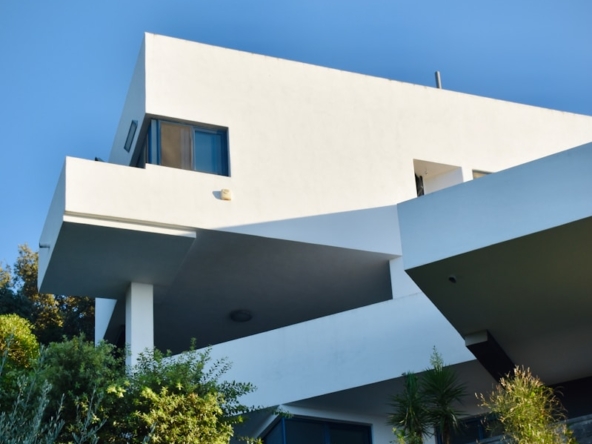 white concrete building near green trees under blue sky during daytime