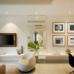 A modern living room with a television, armchair, and framed abstract art